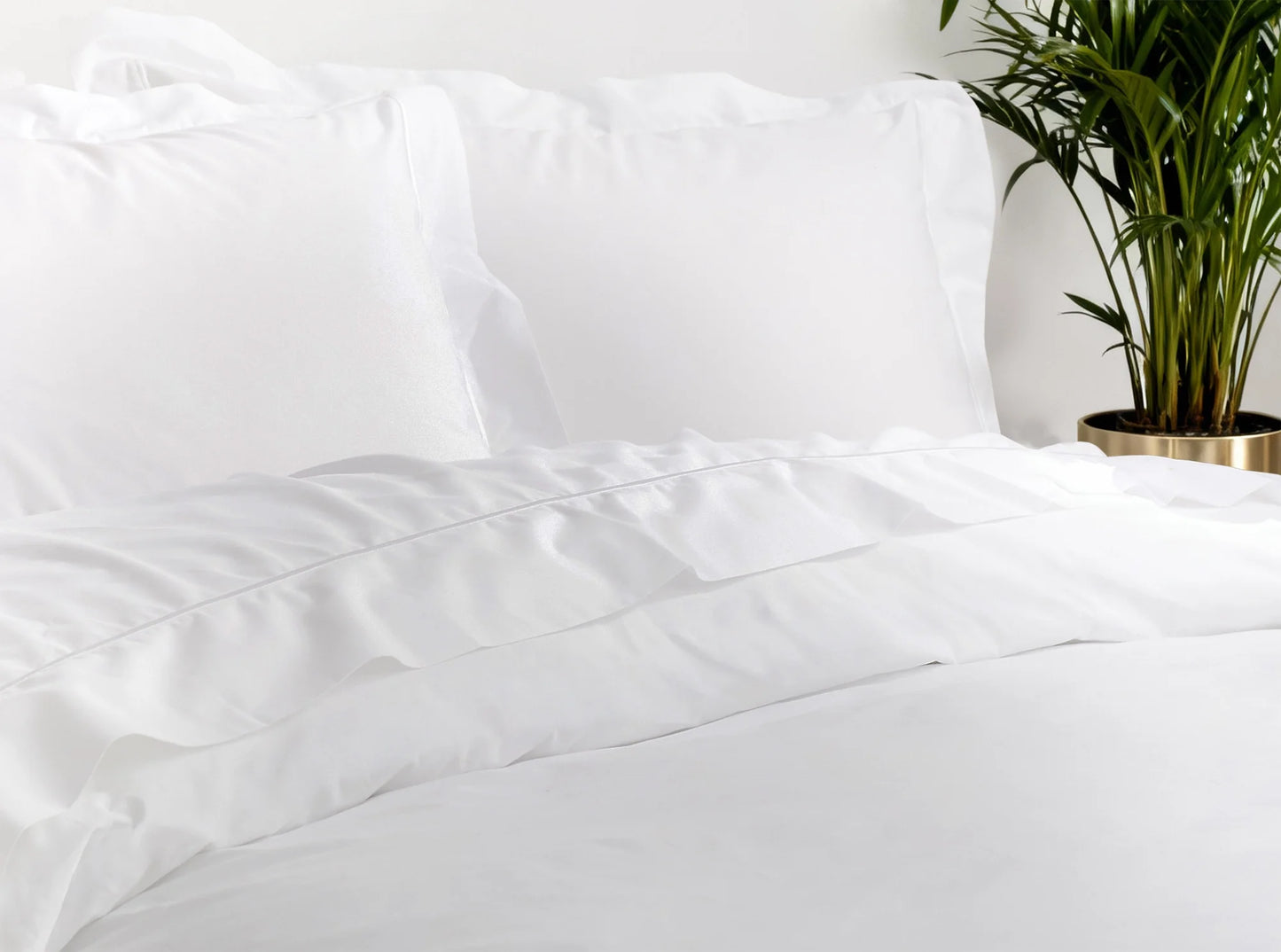 Close-up of white organic cotton percale sheets showing crisp, breathable texture and embroidered detail