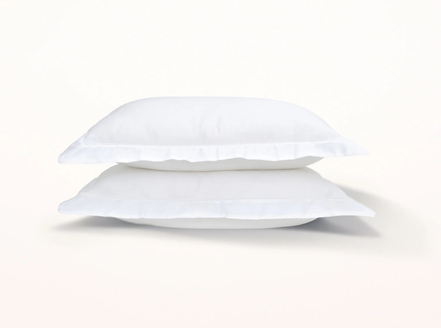 White organic cotton sateen pillowcases stacked, showing hemstitched detail and soft texture